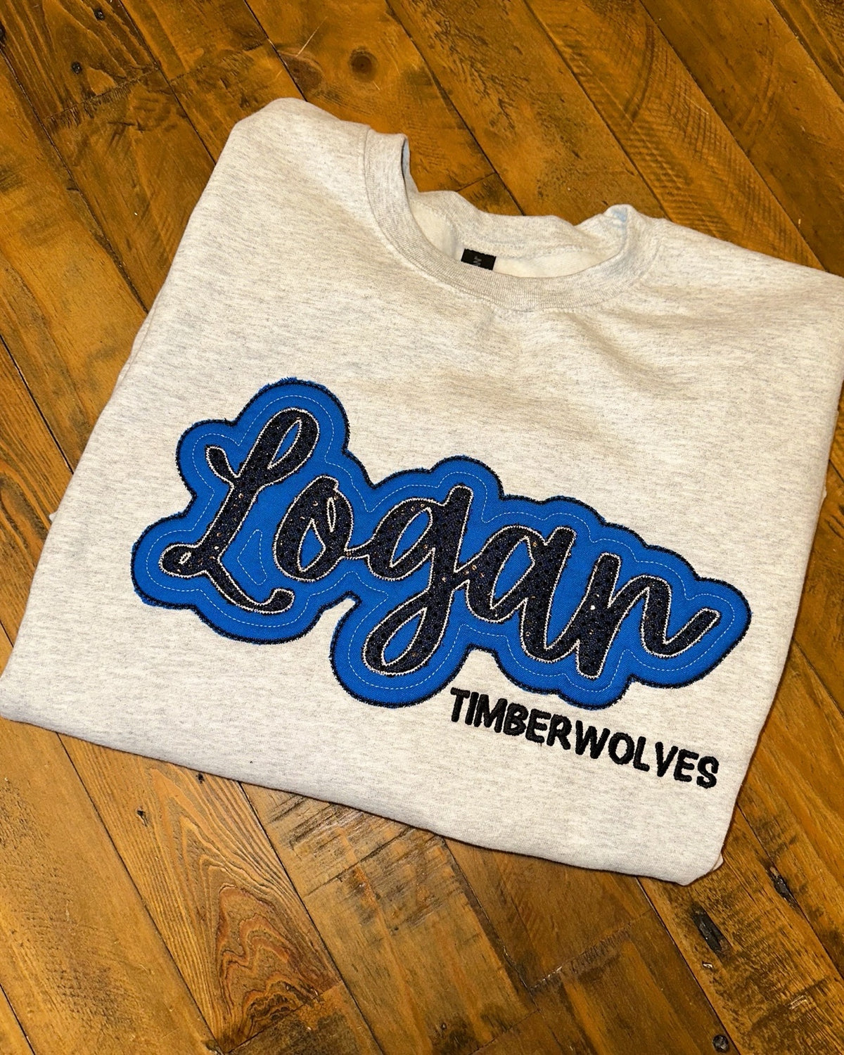 Gray crewneck with blue and black Logan Timberwolves appliqué