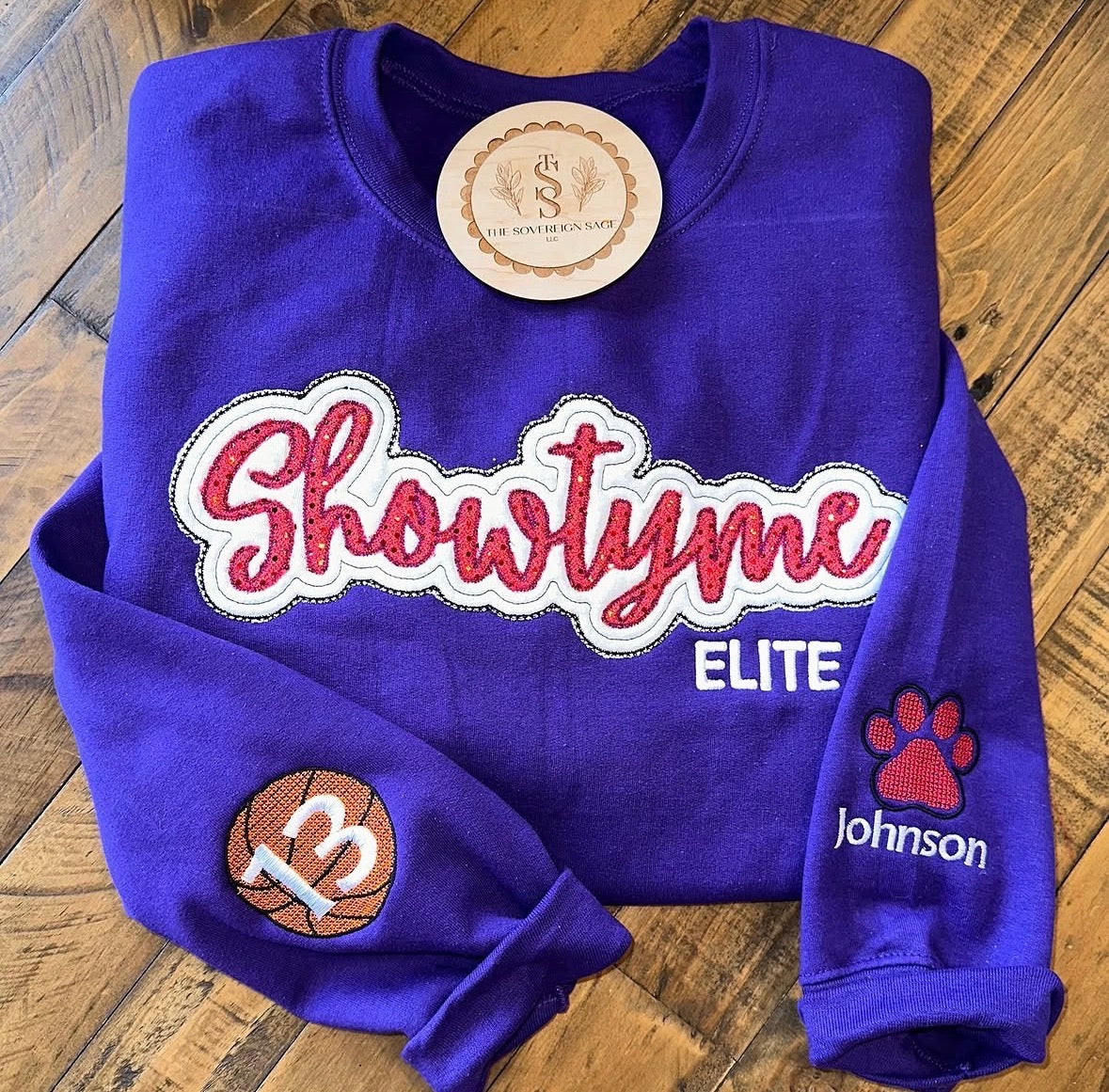 Purple crewneck with Showtyme Elite pink appliqué and embroidered sports sleeves